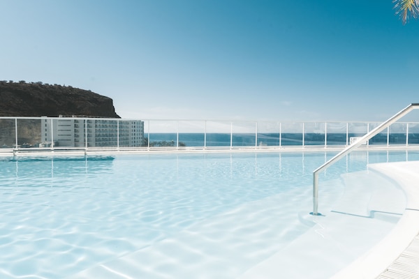 Una piscina al aire libre, sombrillas, tumbonas