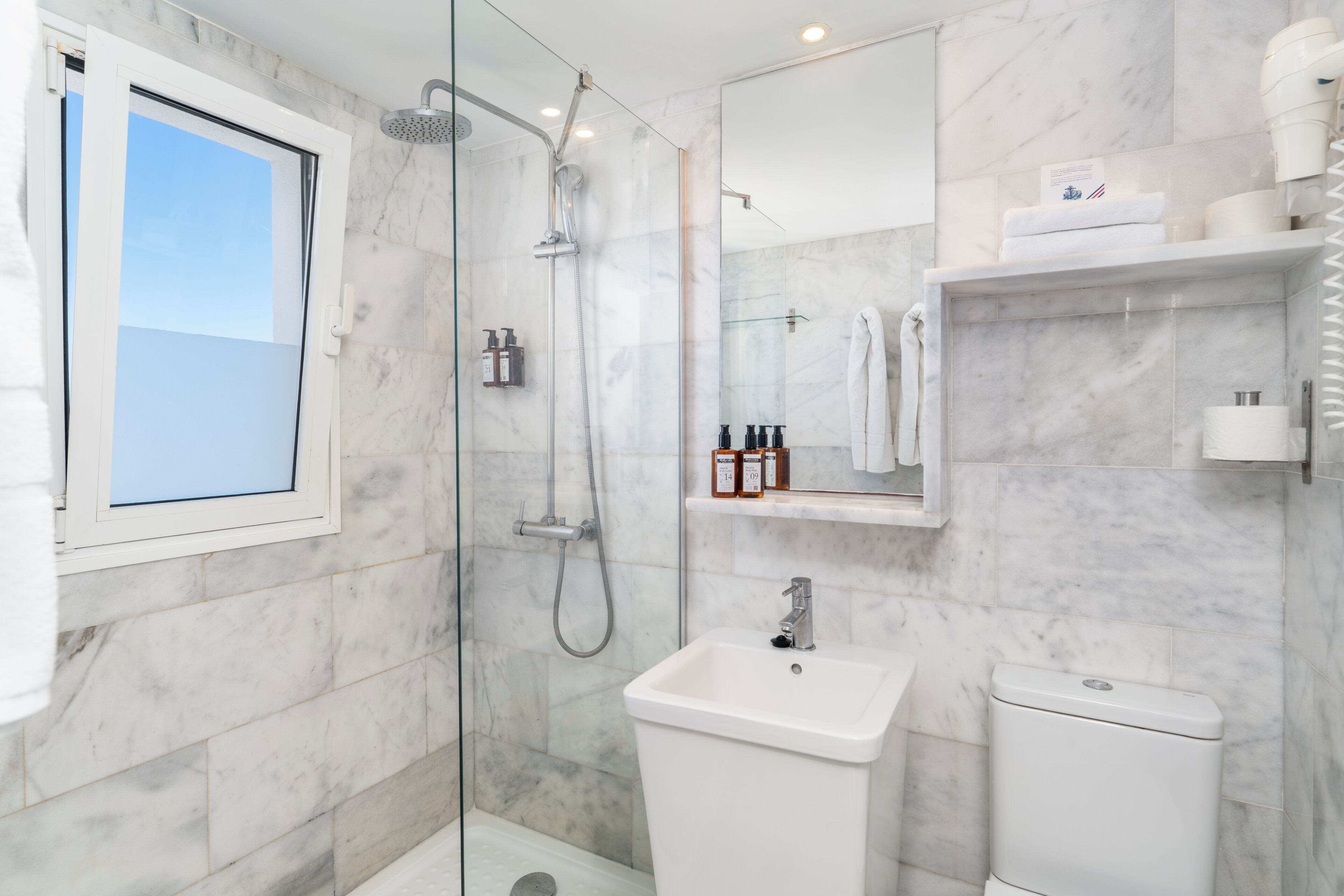 Une salle de bain moderne avec une douche à parois de verre, un lavabo blanc et des toilettes.