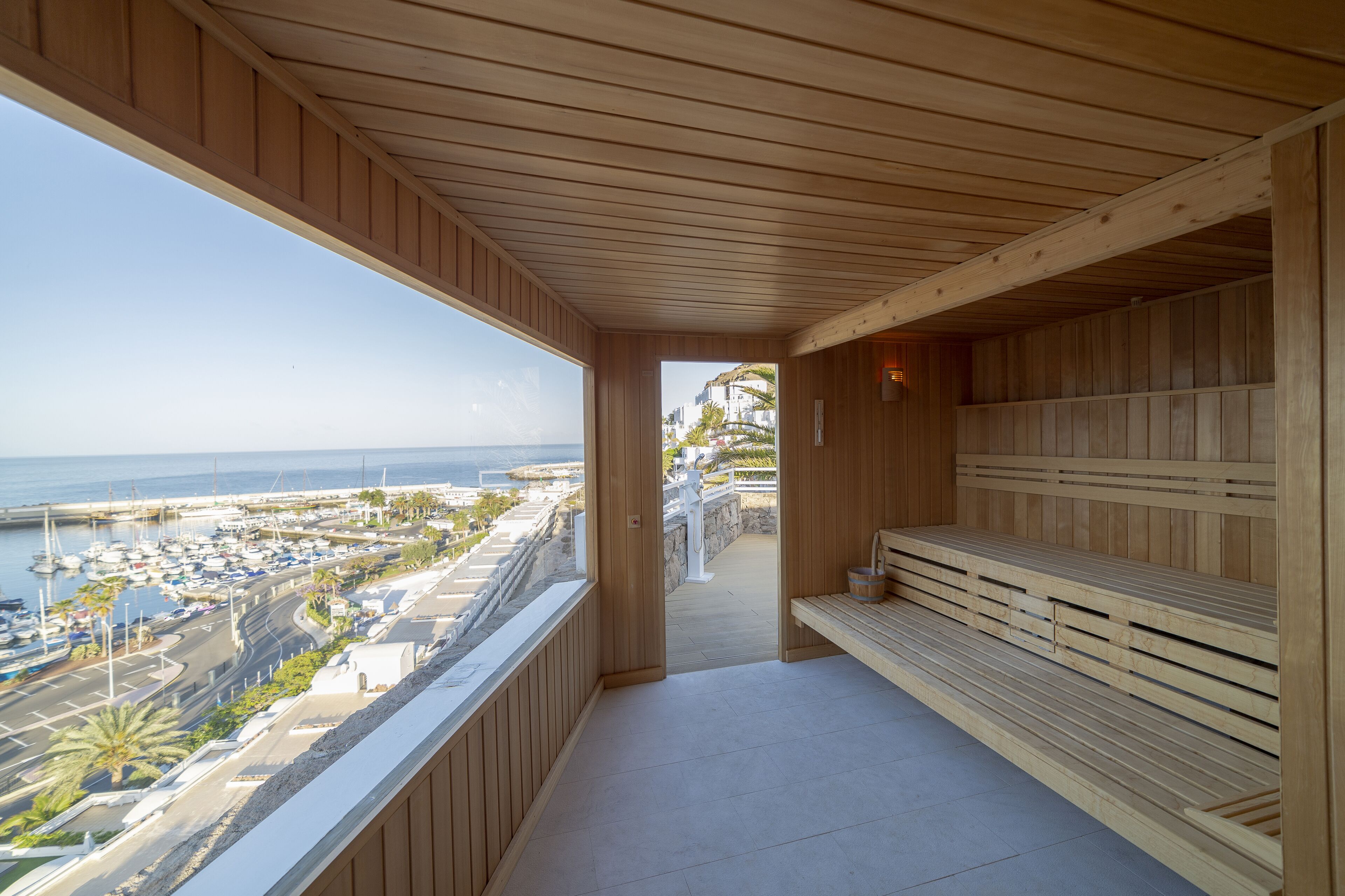 A wooden sauna with benches and a view of the marina and ocean.