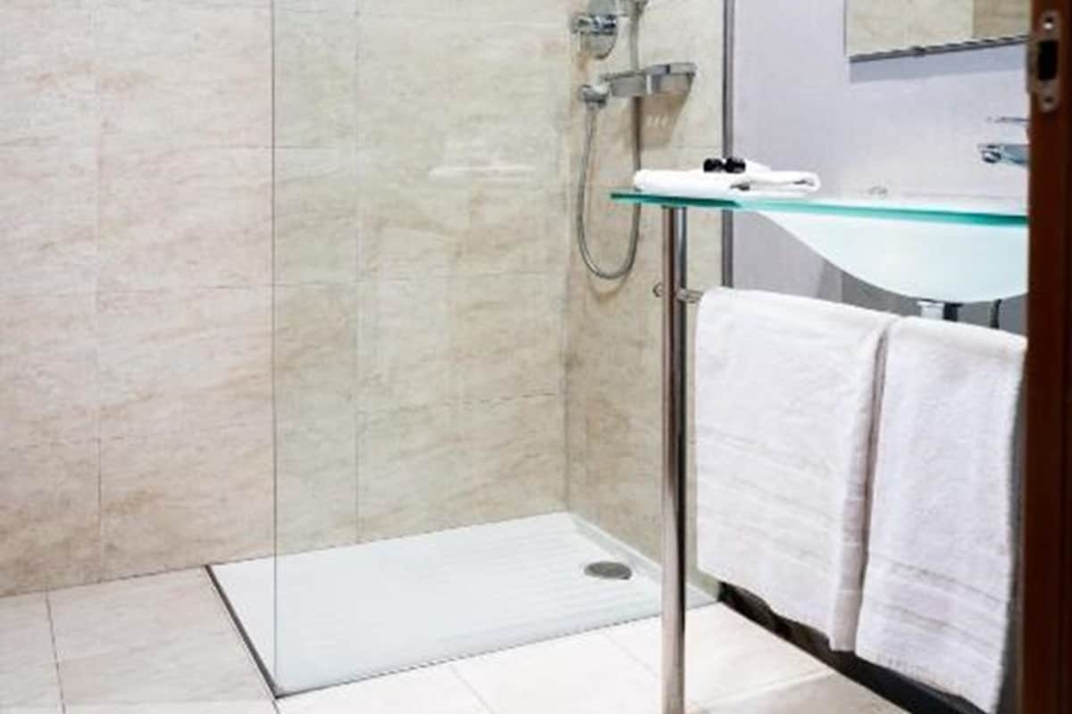 A modern bathroom with a glass shower enclosure, a glass sink, and a mirror.