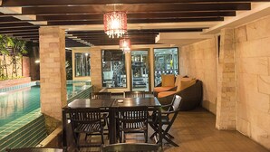 A dining area with a pool view, stone walls, and a chandelier. - Aspen Suites Hotel Sukhumvit 2 Bangkok (Bangkok)