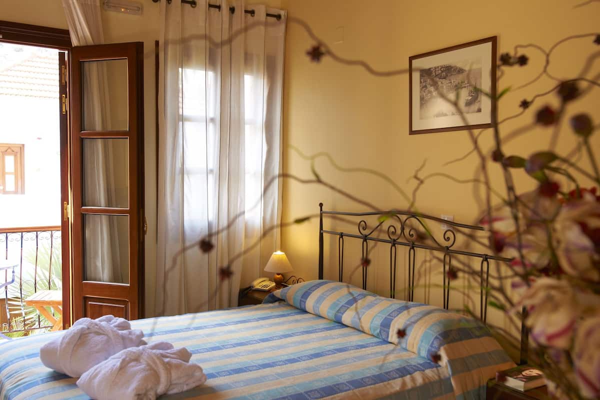 Quarto de hotel com uma cama, mesa de cabeceira, abajur e quadro na parede.