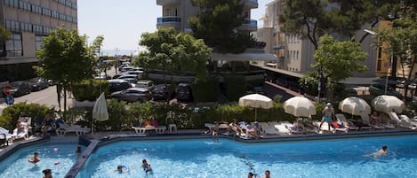 Una piscina al aire libre de temporada, sombrillas, tumbonas