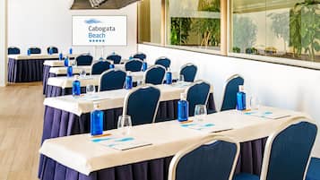 A conference room with tables set for meetings, featuring blue chairs and water bottles.