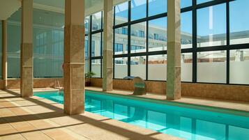An indoor swimming pool with clear views of the building's architecture and a tiled floor.