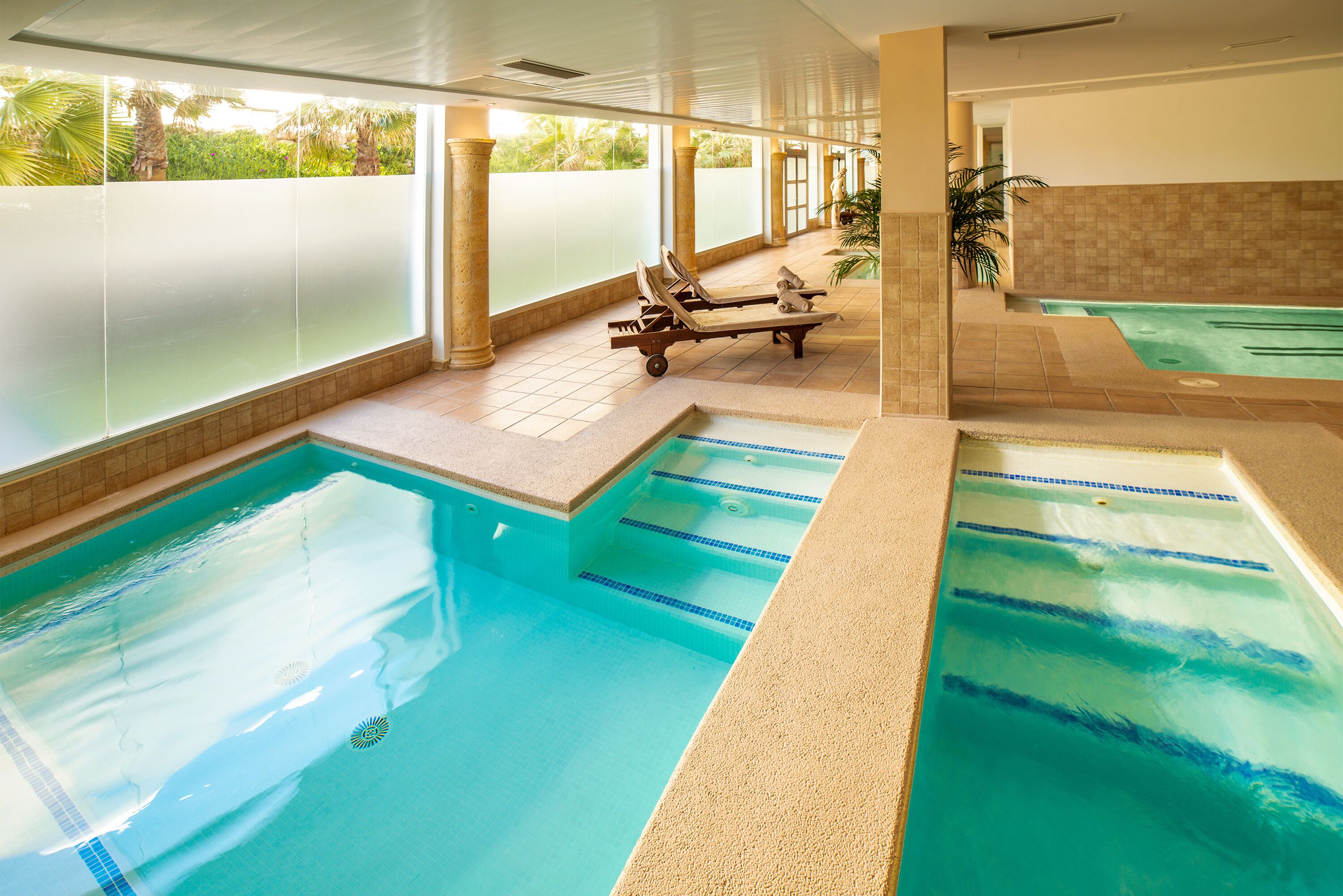 Zona de piscina con sillas de descanso y un jacuzzi aparte.