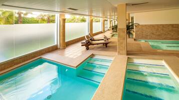 Zona de piscina con sillas de descanso y un jacuzzi aparte.