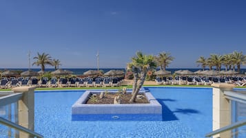 Relax by the oceanfront pool surrounded by lounge chairs and palm trees.