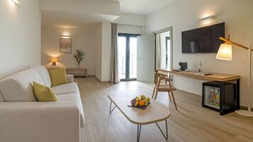 A modern living room with a sofa, a coffee table with fruit, a TV, and a small refrigerator.