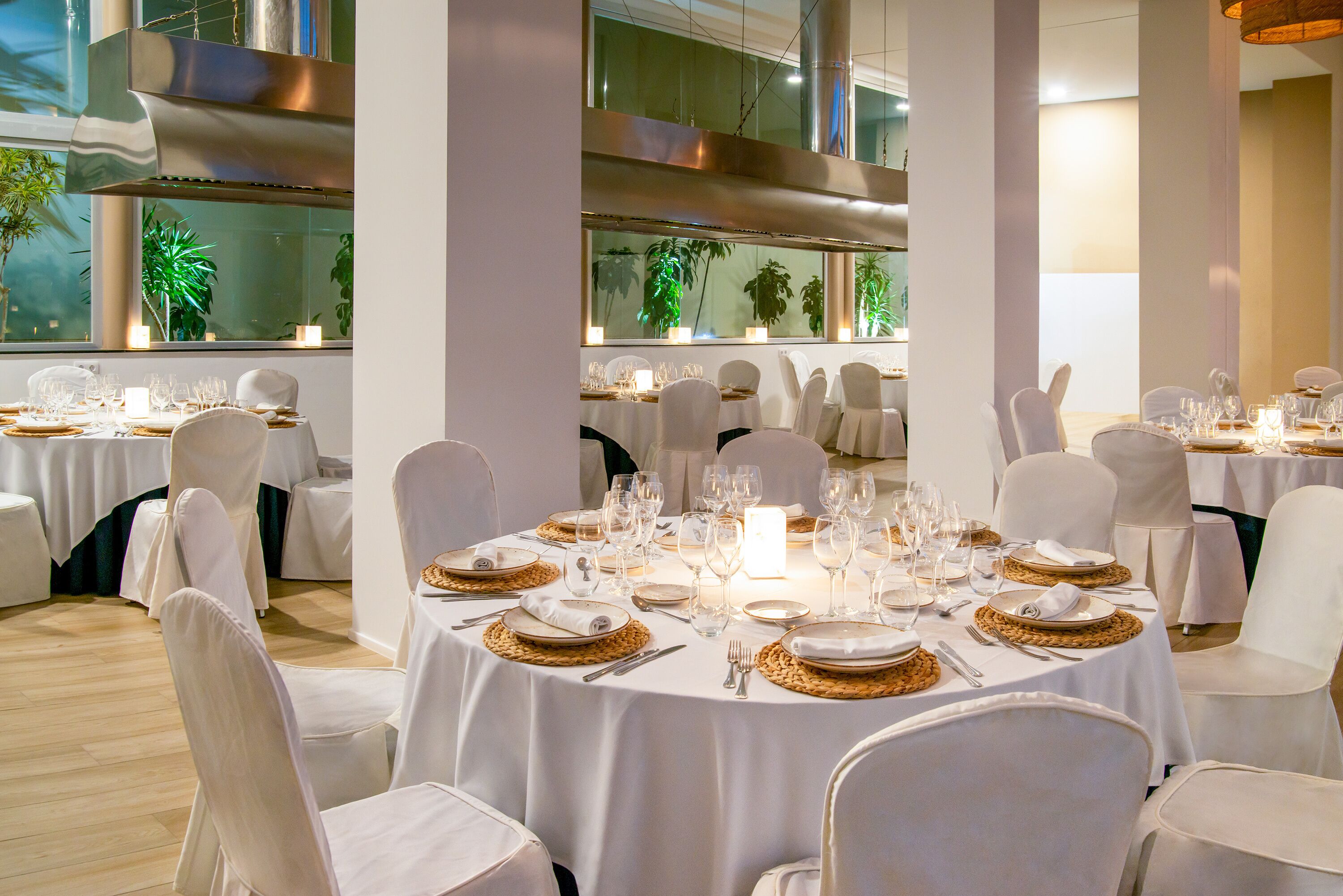 Un restaurante con mesas redondas dispuestas para comer, sillas blancas y una decoración de diseño moderno.