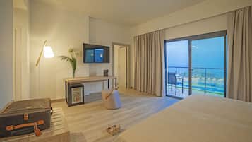 Een moderne hotelkamer met een groot bed, een flatscreen televisie, een minibar, een zithoek met een plant en een balkon met uitzicht.