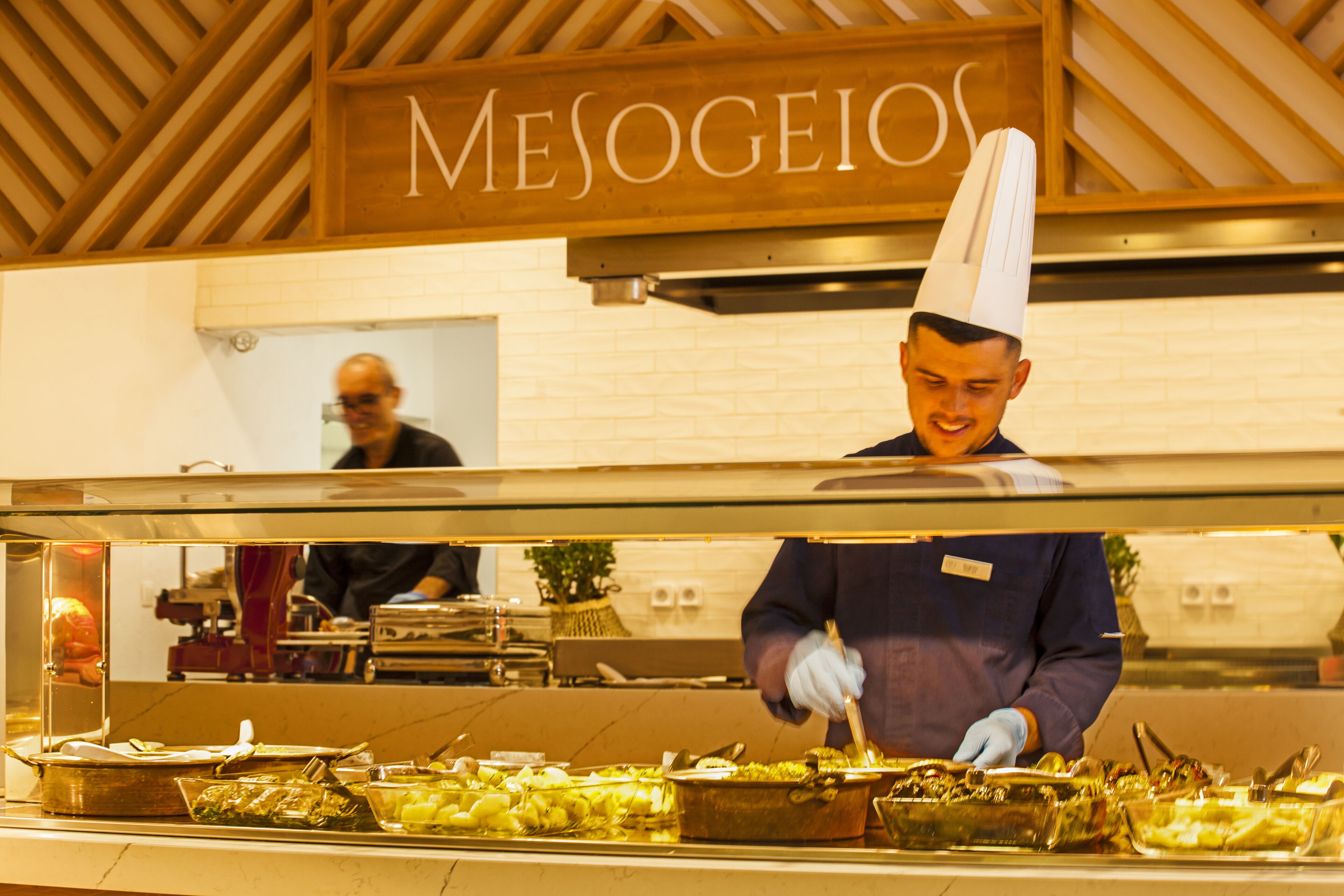A buffet setup with various food items and a chef serving.