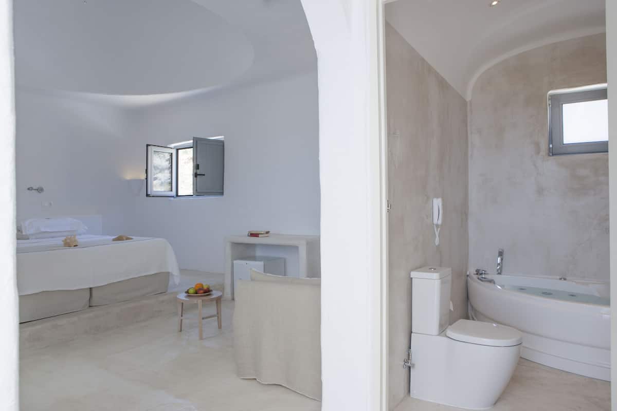 A modern bathroom with a bathtub, toilet, and a small table with fruits.