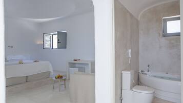 Un baño moderno con bañera, inodoro y una pequeña mesa con frutas.