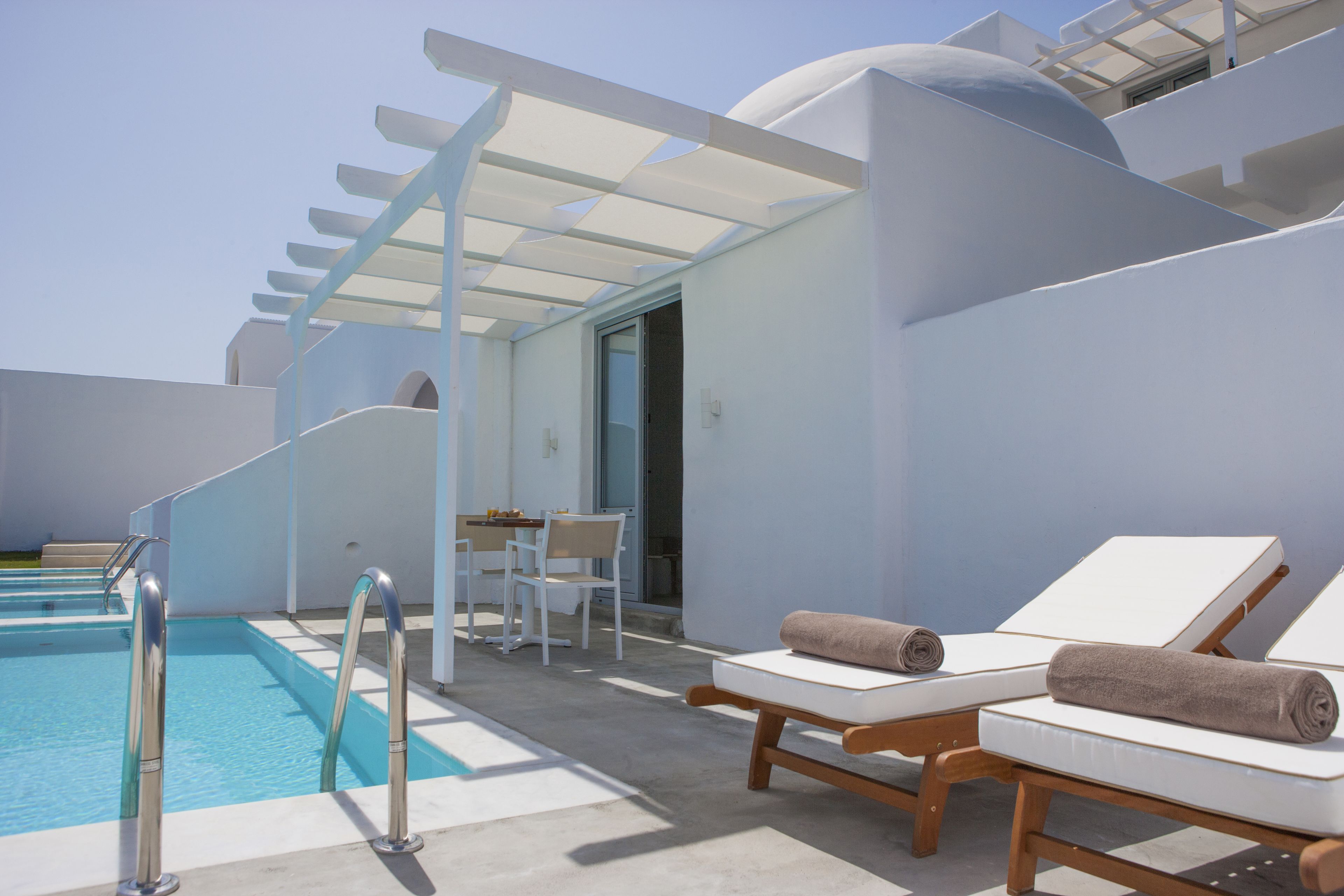 Una piscina al aire libre, sombrillas, sillones reclinables de piscina