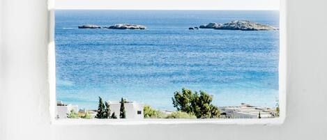 A view through an arched window of a coastal scene with the sea and distant land.