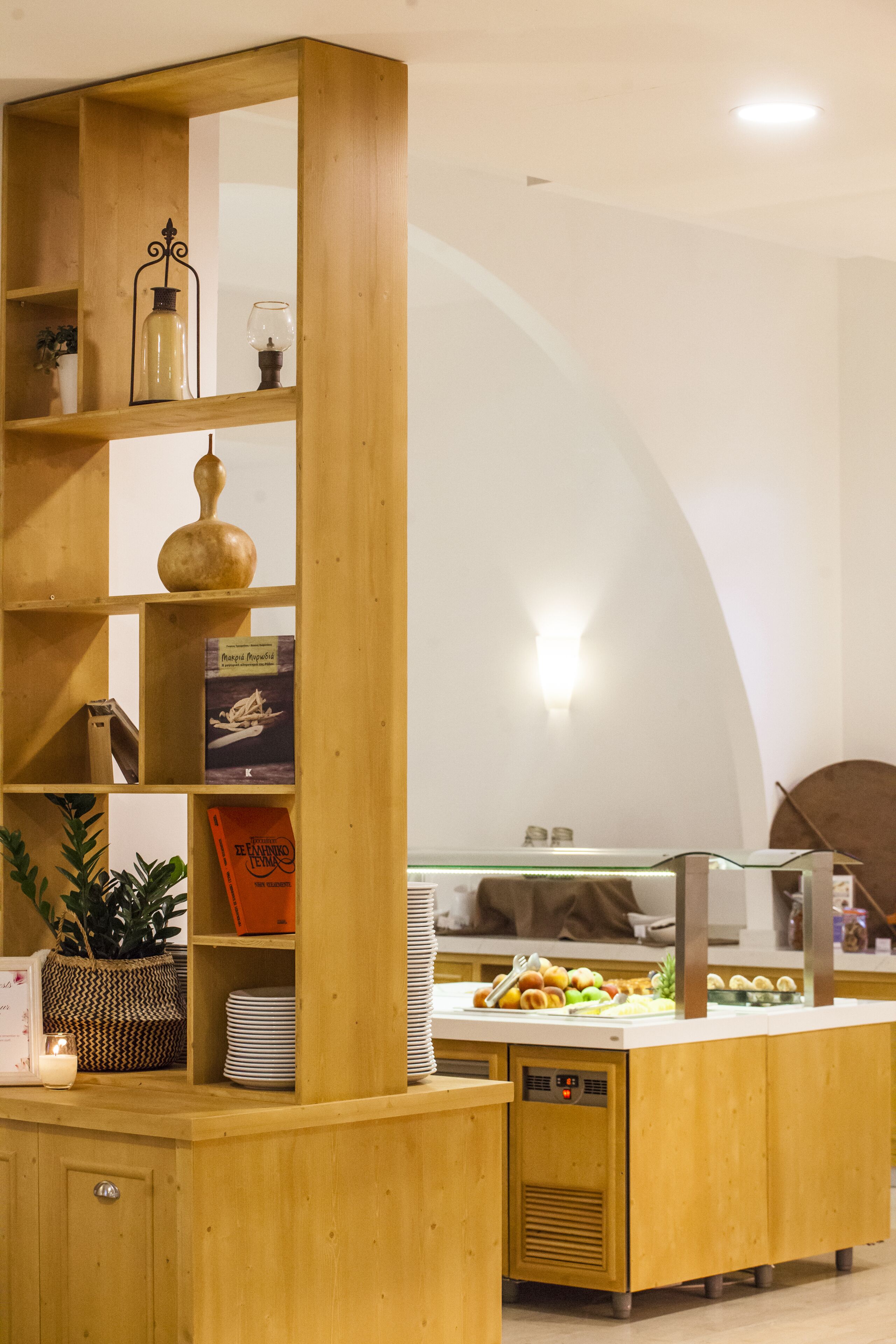 Zona de bufé con estantes de madera, vitrina de vidrio y diversas opciones de comida.