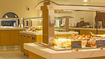 Zona de buffet con diversas opciones de comida y una cocina al fondo.