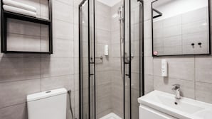 A modern bathroom with a glass-enclosed shower, a white sink, and a towel rack. - Hotel Delta (Kraków)