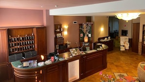 A reception area with a wooden desk, a bulletin board, and a wall-mounted light fixture. - Hotel Belvedere (Alice Bel Colle)