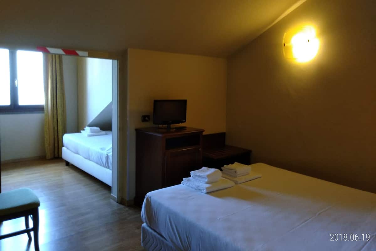 Une chambre d’hôtel avec deux lits, une télévision, un bureau et une chaise.