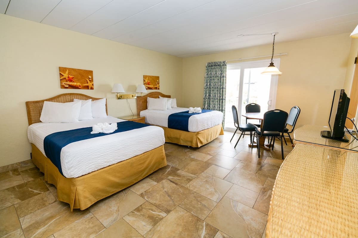 A hotel room with two beds, a dining area, and a TV.