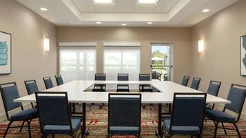 A conference room with a large rectangular table, blue upholstered chairs, and a carpeted floor.