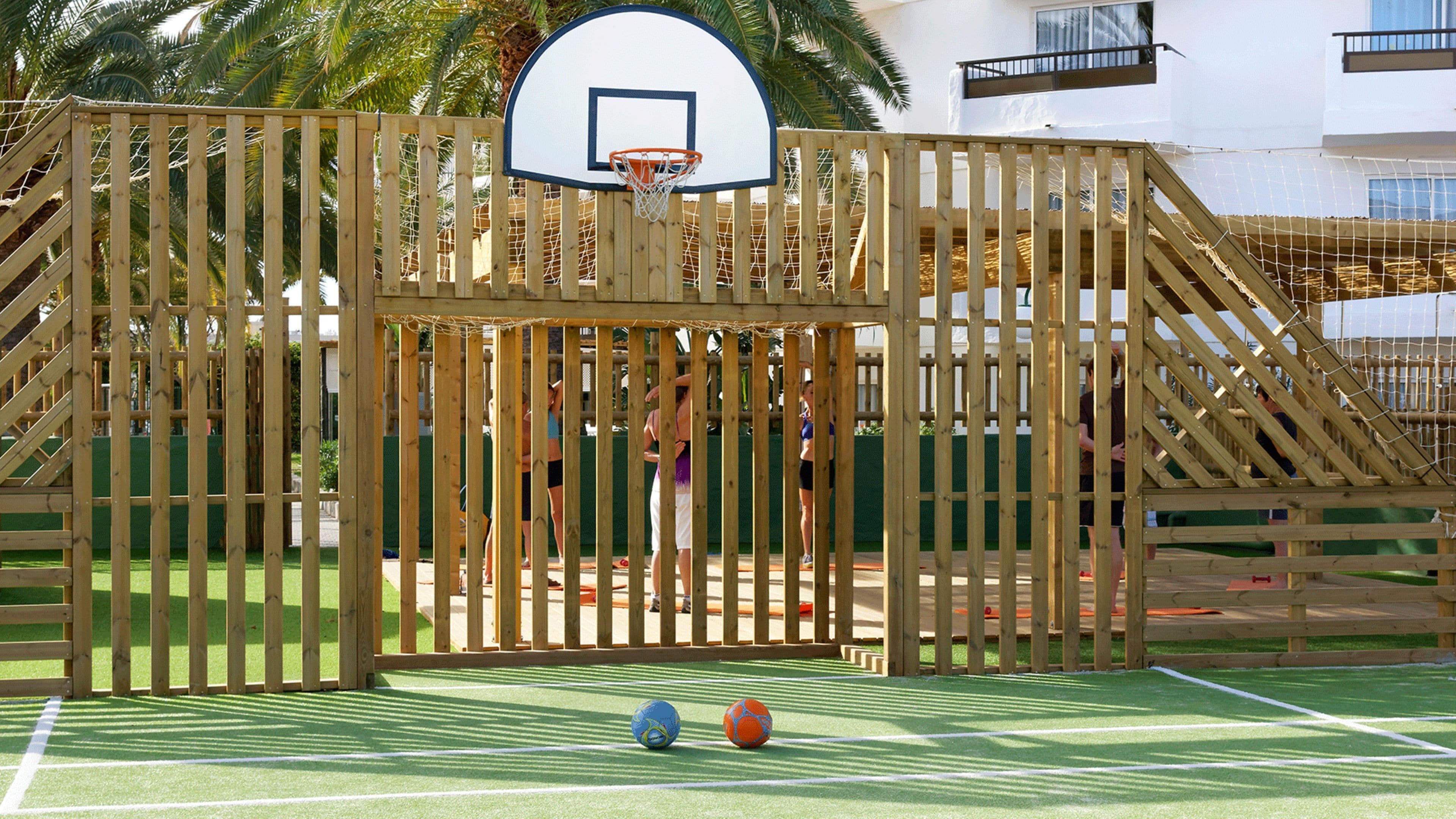 A basketball court with a wooden fence and a basketball hoop.