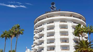 Un hotel de varios pisos con un diseño circular, que cuenta con balcones y un logotipo destacado en la parte superior.