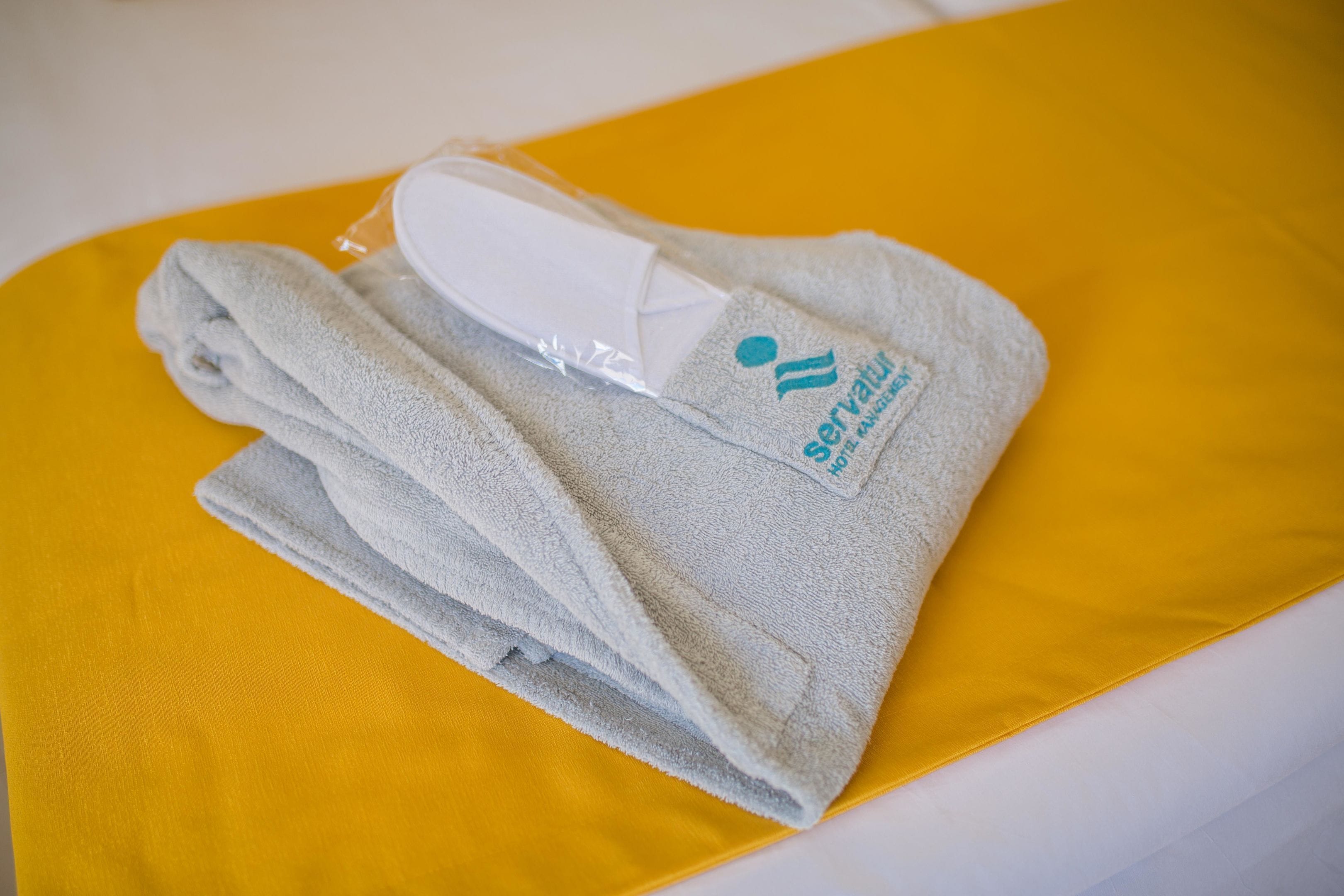 Een gevouwen handdoek met een logo op een geel kussen.