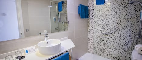 Une salle de bain moderne avec un lavabo blanc, un miroir, une douche et des toilettes.