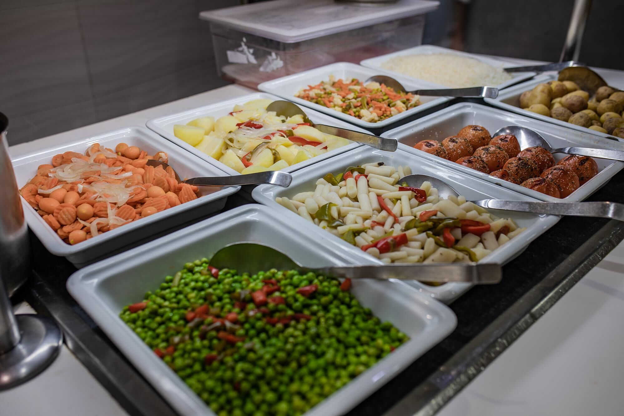 Un bufé con diversas opciones de comida, incluyendo pasta, verduras y platos de carne.