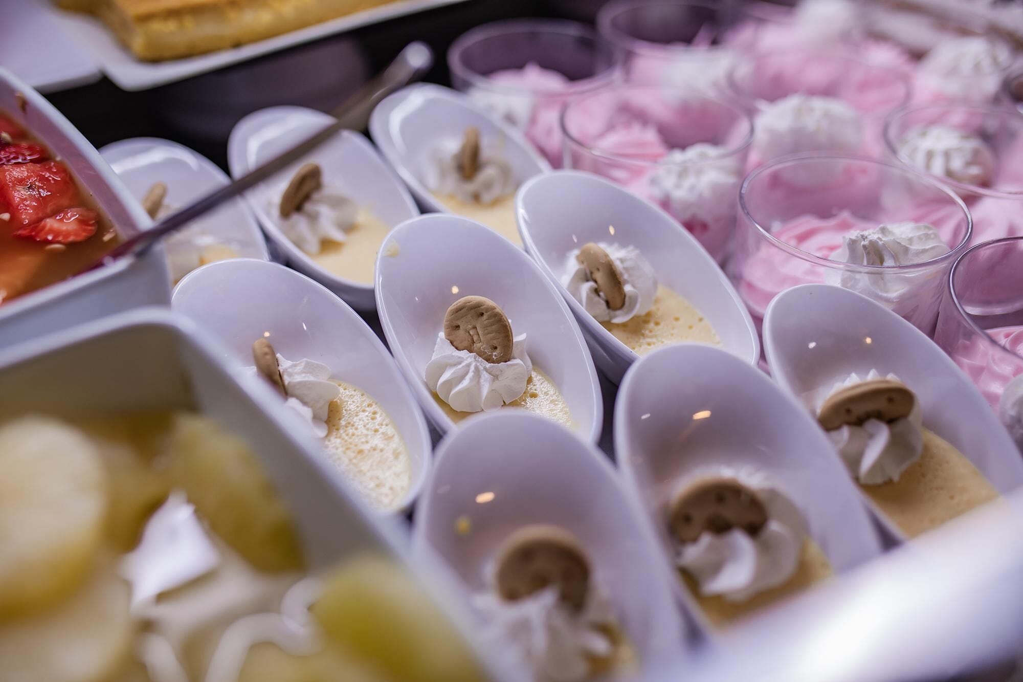 Vasitos de postre con crema batida y galletas, dispuestos sobre una mesa.