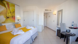 A hotel room with two beds, a desk, a chair, a mirror, and a bathroom door. - Servatur Waikiki (San Bartolomé de Tirajana)