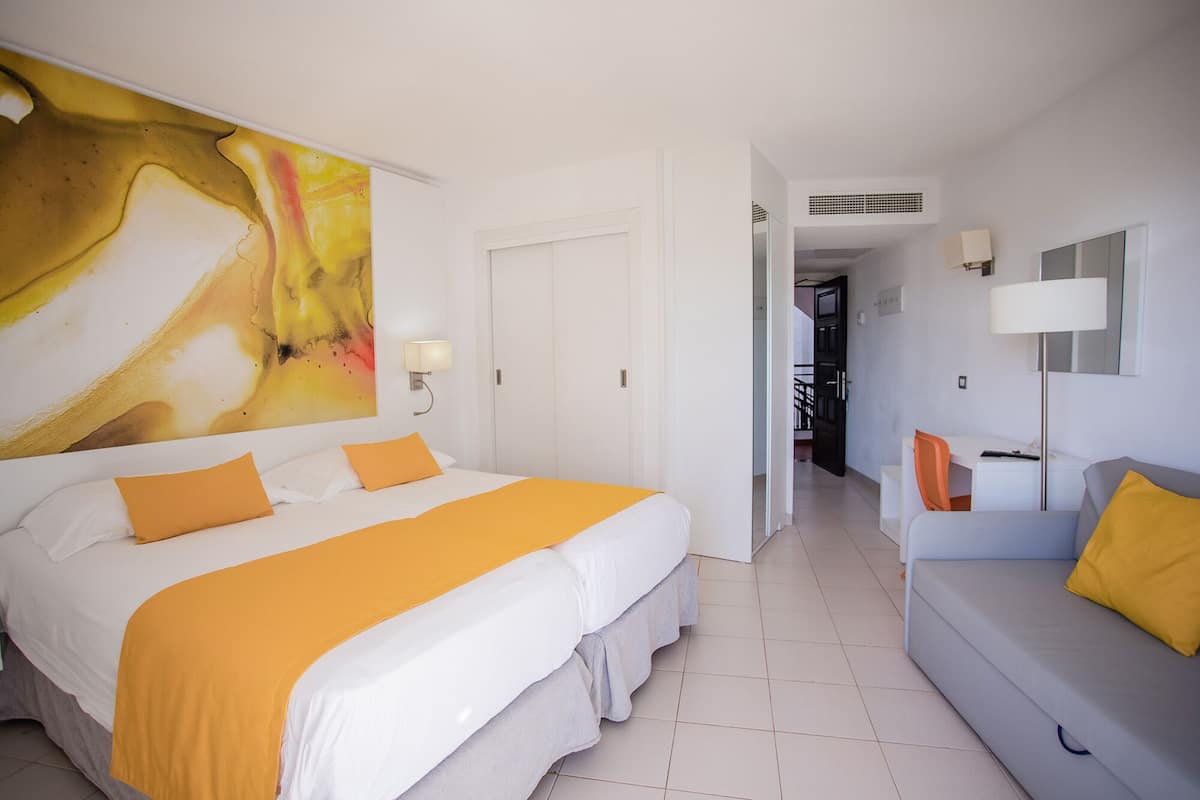 A hotel room with a large bed, a desk, and a sofa.