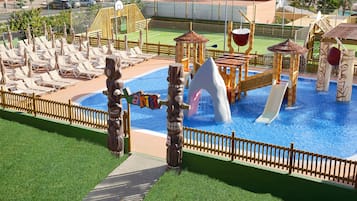 Relax by the clear blue pool surrounded by lounge chairs and umbrellas, with a totem pole and play structures nearby.