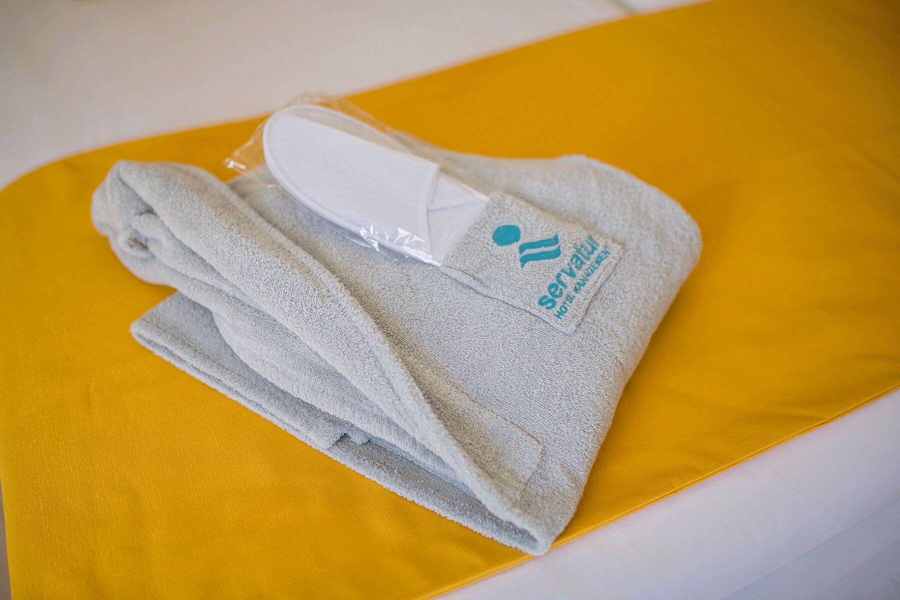 A folded towel with a logo and text on it, placed on a yellow pillow.