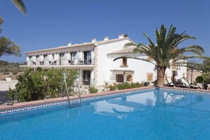 A hotel with a swimming pool, a white building with balconies, and a palm tree. - Sa Bassa Plana (Llucmajor)