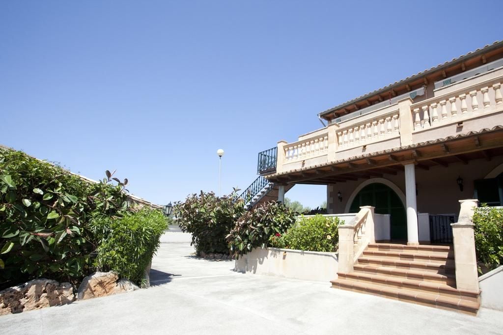 A building with a staircase leading to a balcony, surrounded by greenery.