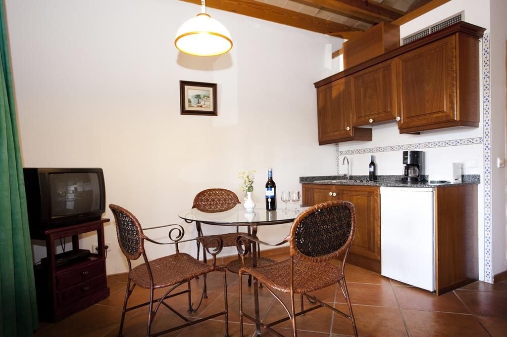 A compact kitchen with a dining area, wooden cabinets, a television, and a small island with a coffee maker.