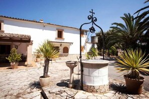 A courtyard with a white building, a stone fountain, and potted plants. - Sa Bassa Plana (Llucmajor)
