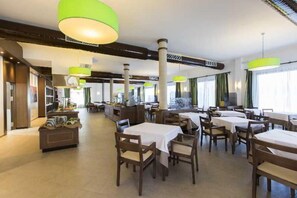 A spacious dining area with multiple tables and chairs, high ceilings, and large windows allowing natural light. - Sa Bassa Plana (Llucmajor)