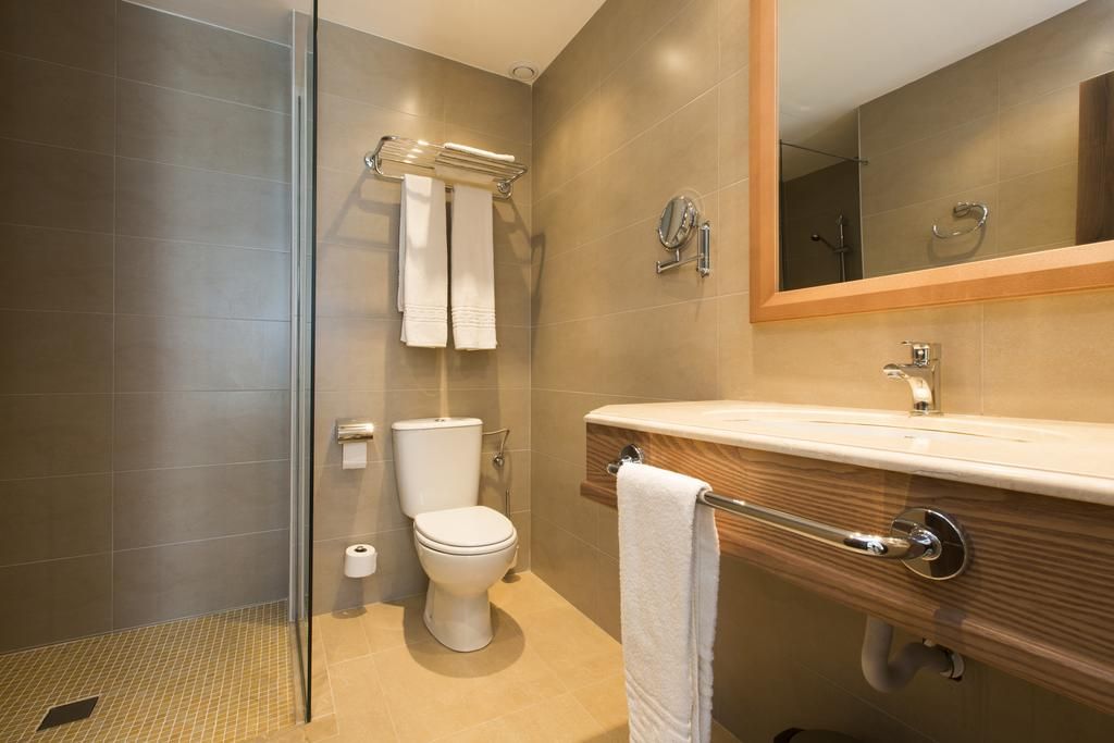 A modern bathroom with a glass shower enclosure, a toilet, and a vanity with a mirror.