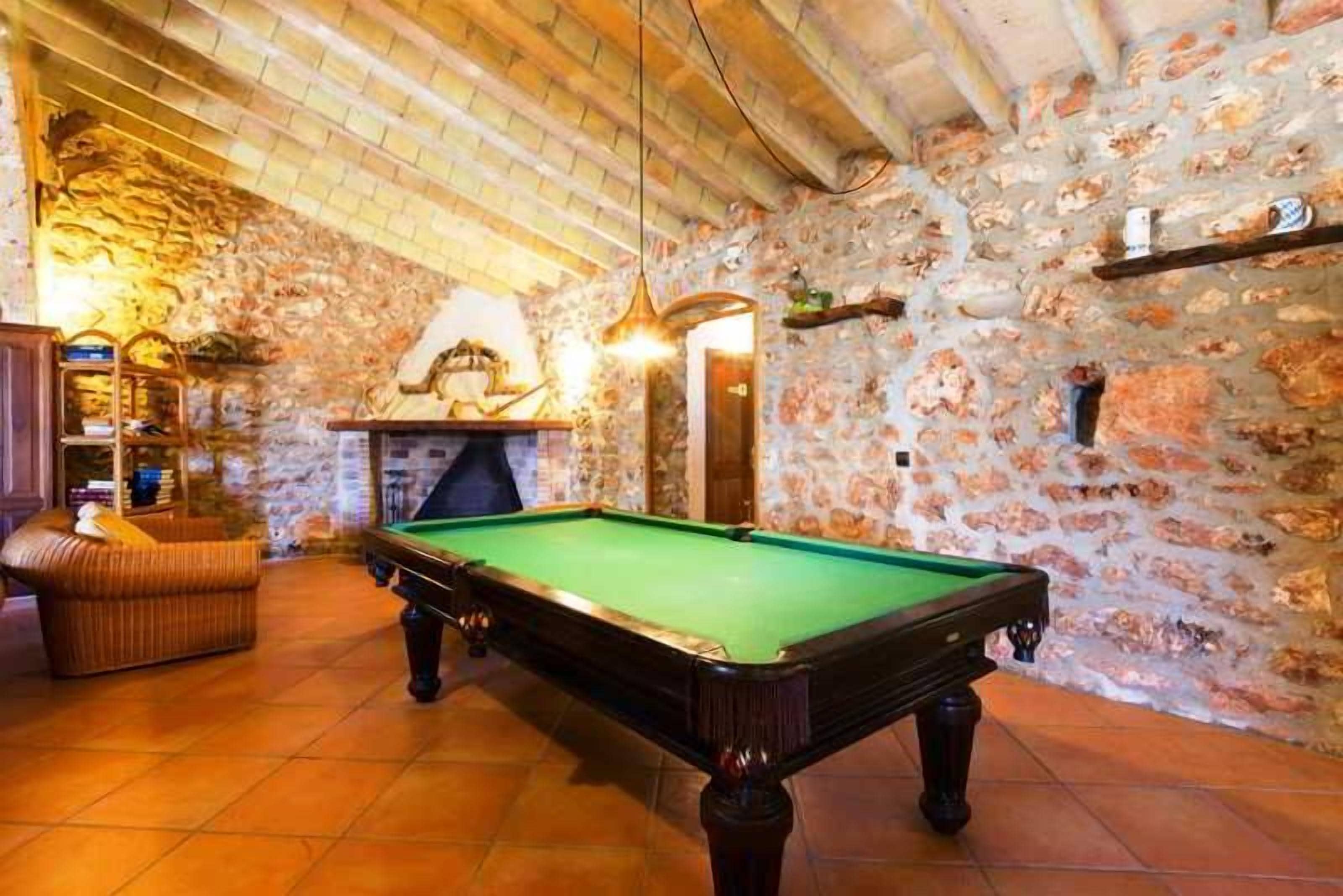 A billiards table in a room with stone walls and a tiled floor.