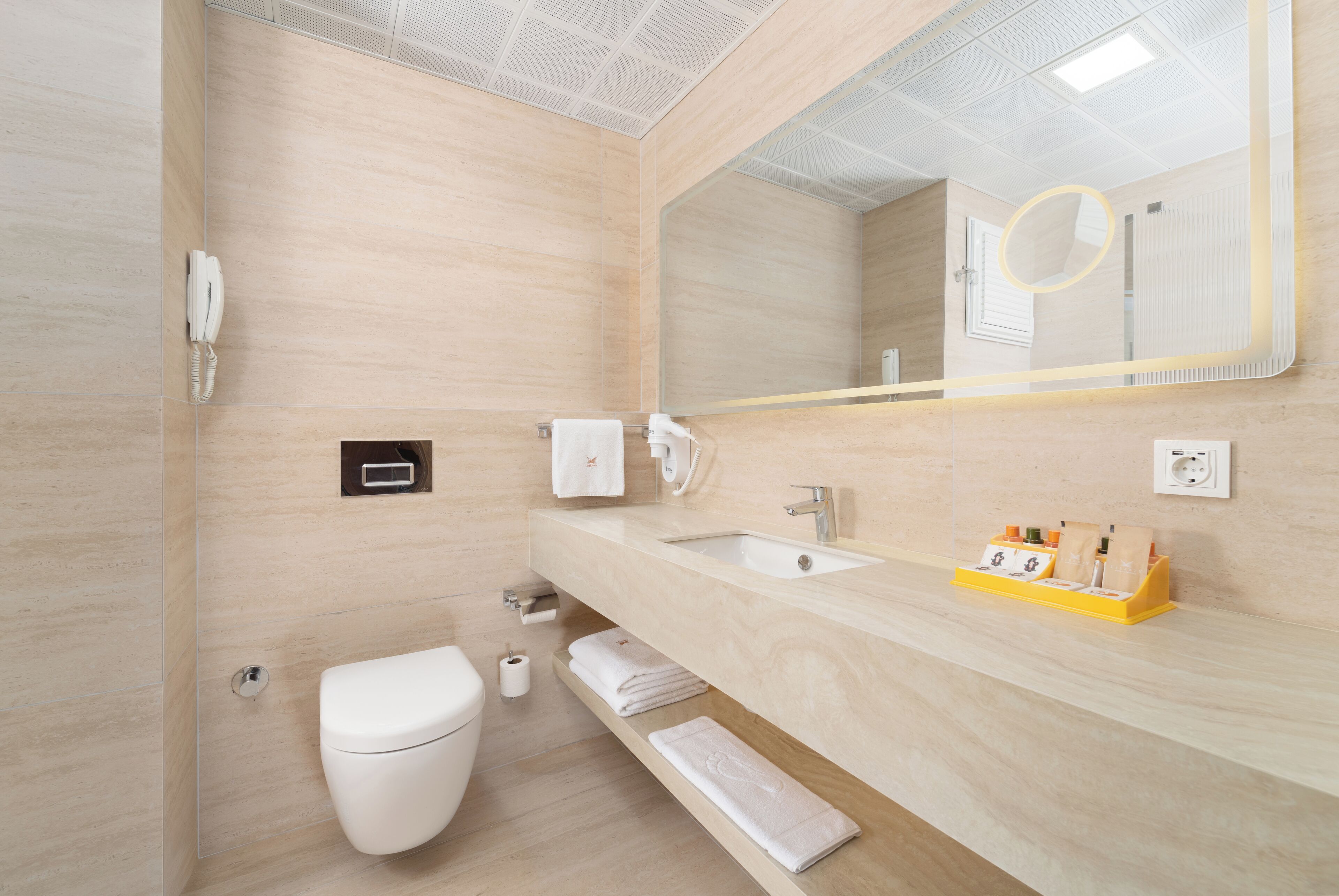 A modern bathroom with a toilet, sink, and mirror.