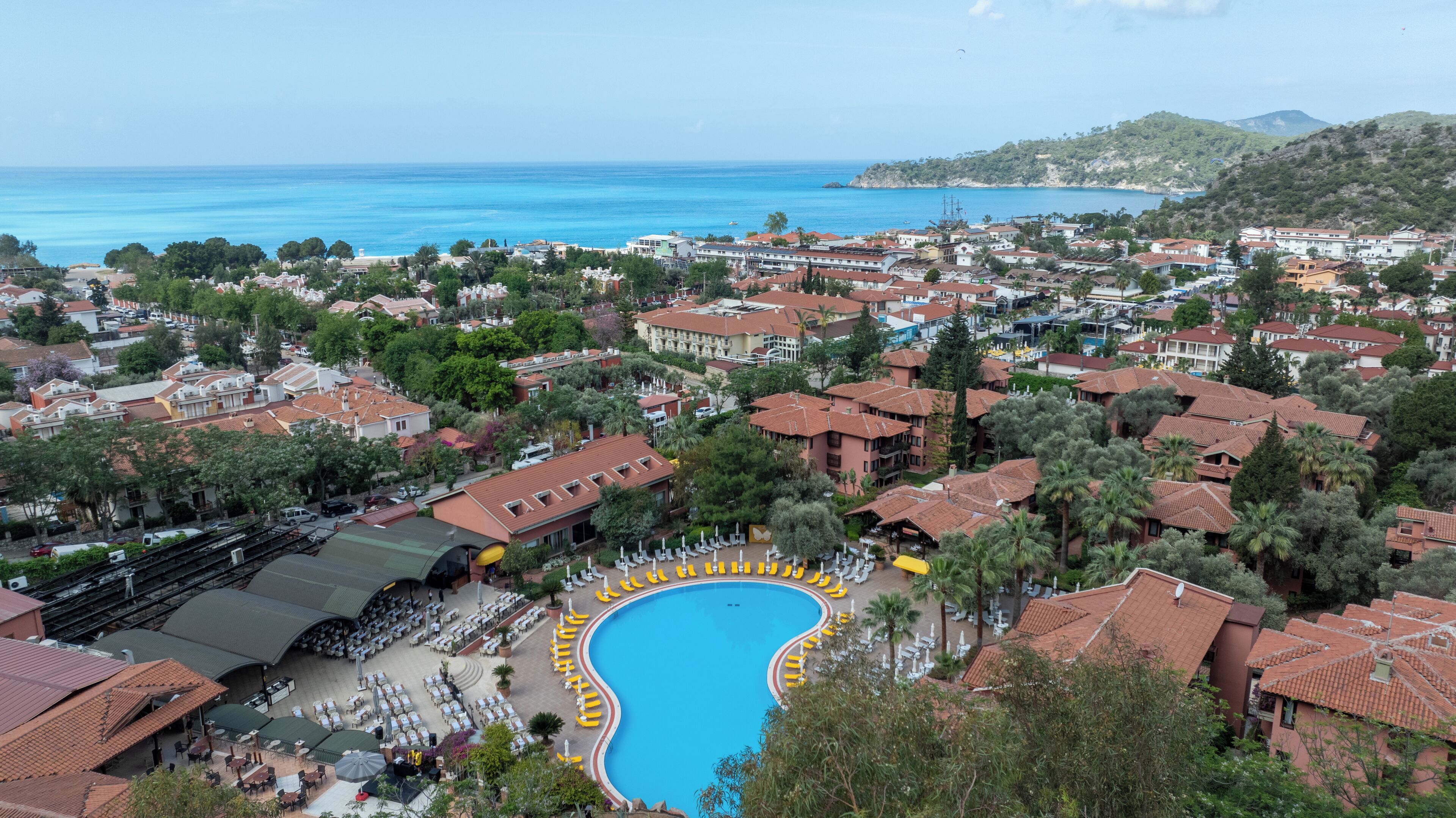 Ein Resort mit einem großen Pool, umgeben von Villen und Blick auf das Meer.