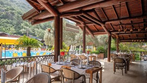 An outdoor dining area with tables and chairs, overlooking a pool and lush greenery. - Sundia By Liberty Suncity - All inclusive (Fethiye)