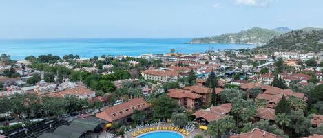 A resort with a large swimming pool, multiple buildings, and a view of the sea.