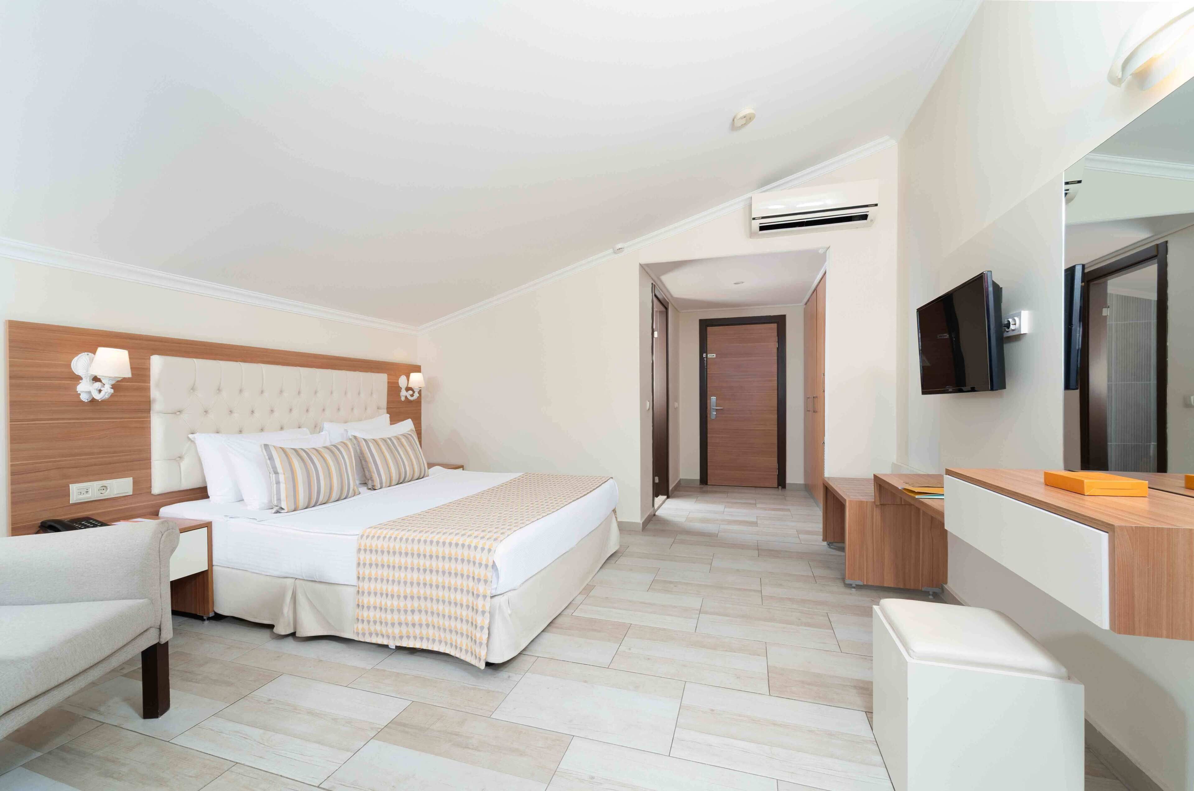 A hotel room with a bed, bedside table, chair, and a TV.