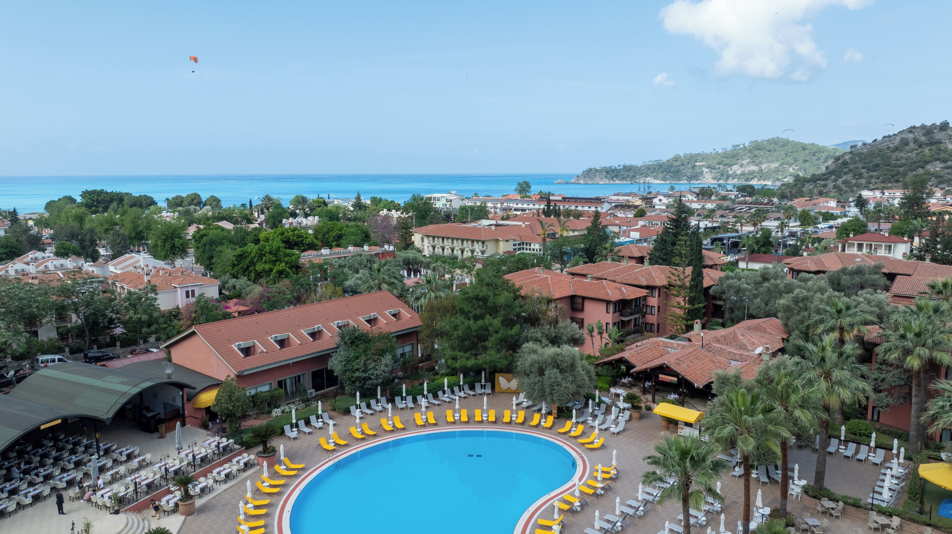 Un complexe hôtelier doté d’une grande piscine, de chaises longues et offrant une vue sur la mer.